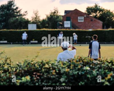 Lawn bowls players / bowlers in whites at a summer evening tournament  game in rural England Britain UK - British summer bowling green club Stock Photo