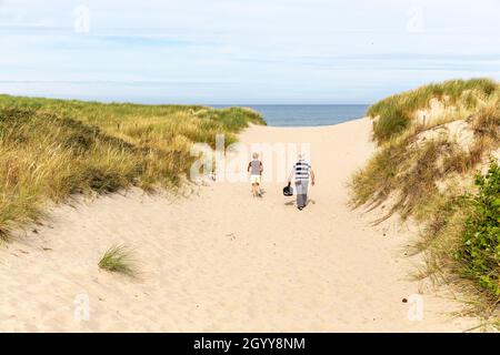 Couple crossing the cordon of dunes to access the beach Stock Photo