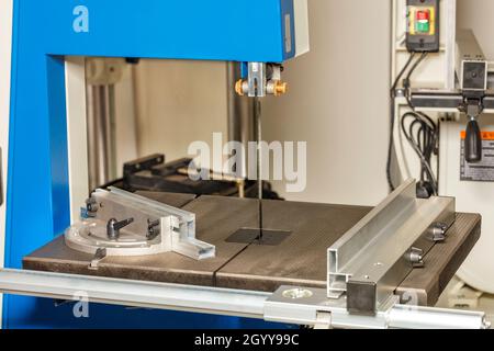 Professional industrial machine with a blue casing for sharpening chains of chainsaws close-up on a gray-beige background. Stock Photo