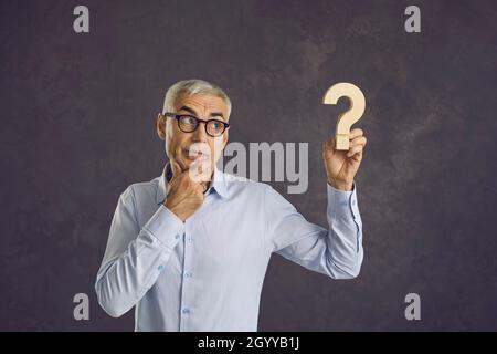 Unsure man hold question sign thinking pondering Stock Photo