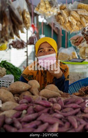 Kuala Lumpur, Malaysia - September 18, 2021 Woman seller wearing face mask at the local ingredients fresh food stall. Stock Photo