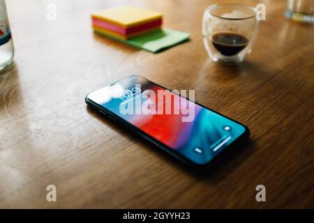A smartphone, a transparent glass with some coffee, and sticky notes on a wooden table Stock Photo