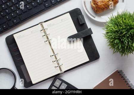 high angle view of open notepad and office stationary on white  Stock Photo