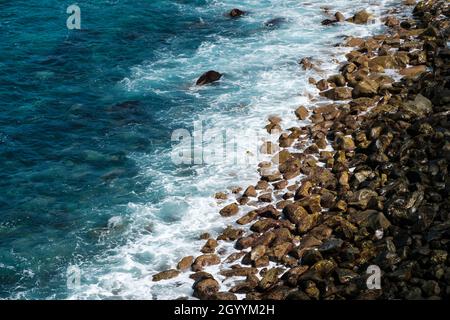 ocean waves hitting black stone beach, rocky coast landscape Stock Photo