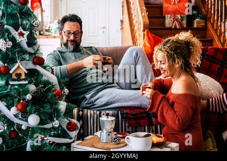 Man with his wife drinking coffee and talking during Christmas celebration at home. Caucasian couple having breakfast on the eve of Christmas. Couple Stock Photo