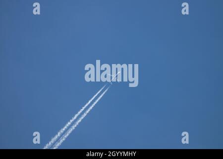 View of a commercial airplane high in the sky with the trails of the turbines Stock Photo