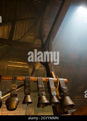 Traditional cowbells are hanging on the attic of a an alpine dairy in Switzerland. Stock Photo