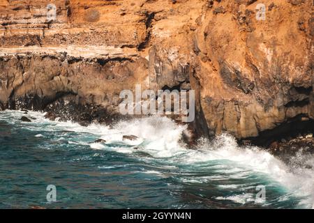 Waves crashing at rocky coast, volcanic shore landscape Stock Photo