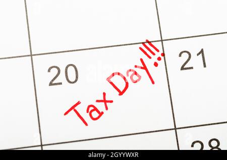 Tax Day red text written on a calendar to remind you and important appointment. Stock Photo