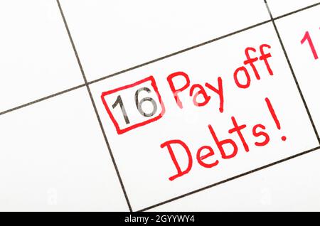 The words Pay off debts written on a calendar to remind you and important appointment. Stock Photo
