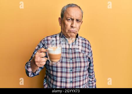 Handsome senior man with grey hair drinking a cup coffee depressed and worry for distress, crying angry and afraid. sad expression. Stock Photo