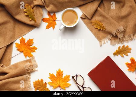 Beige cashmere scarf, coffee cup with autumn maple and oak leaves glasses book on gray background. Flat lay, top view, copy space Stock Photo