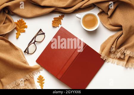 Autumn composition. Open inverted book glasses cashmere scarf, coffee cup with autumn leaves on a white background. Flat lay top view Stock Photo