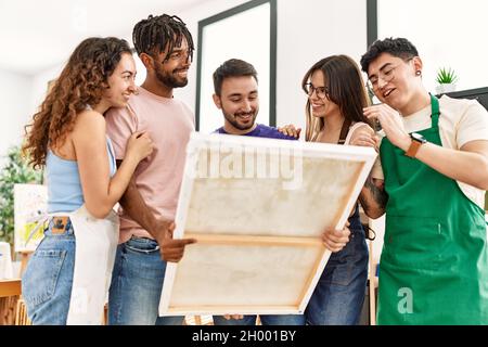 Group of young paint students smiling happy looking canvas standing at art studio. Stock Photo
