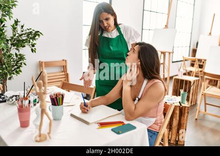 Two latin paint students arguing sitting on the table at art school. Stock Photo