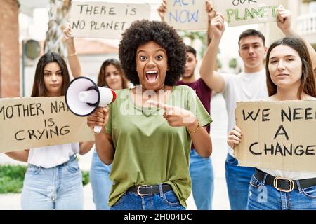 Group of young friends protesting and giving slogans at the street smiling happy pointing with hand and finger Stock Photo