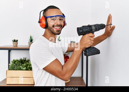 Young hispanic man smiling confident using drill at home Stock Photo