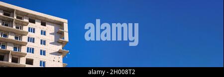 Brick walls of a new residential building. Construction site banner against blue sky background with copy space Stock Photo