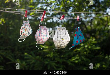 Close up of safety facial masks drying on hanger with clothespins. Pandemic and virus protection concept Stock Photo