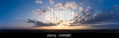 Panorama of orange sunset with clouds and blue sky. Stock Photo