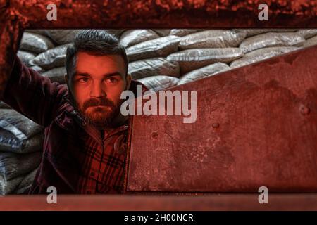 A young man looking into a solid fuel boiler, working on biofuel, economical heating. Stock Photo