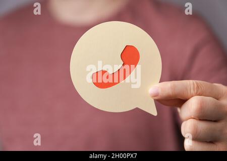 A person holding a talk bubble with a call sign on it, contact support Stock Photo