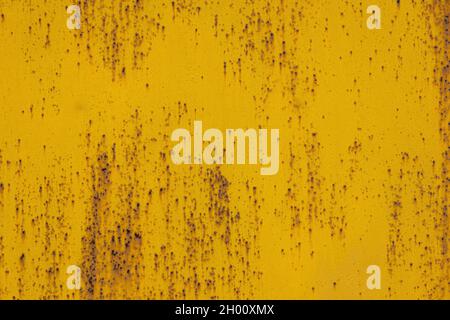 full frame background and texture of yellow painted sheet steel with multiple rust spots on it Stock Photo