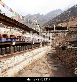 Buddhist prayer many wall with prayer wheels in nepalese village, round Annapurna circuit trekking trail, Nepal Stock Photo