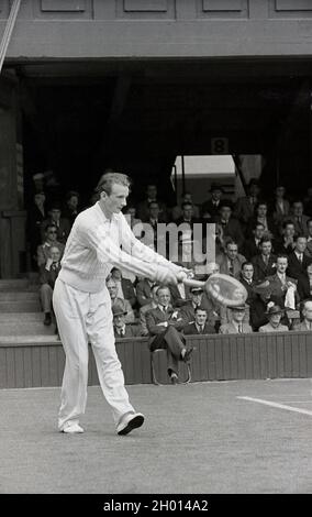 1930s, historical, a male tennis player wearing long trousers and a woollen sweatear, serving on a grass court at the famous Wimbledon tennis championships, owned and run by the All England Lawn Tennis & Croquet Club, founded in 1868. The first gentleman's tennis championships were held in 1877, when the service motion was underarm. Stock Photo