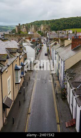 looking along Conway high street toward the well preserved 13th century medieval Conwy castle, an imposing fortress in North Wales Stock Photo