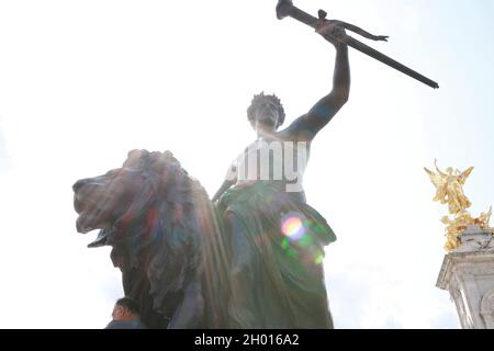 A low angle shot of a bronze statue of a man holding a flaming torch in Buckingham Palace, London Stock Photo