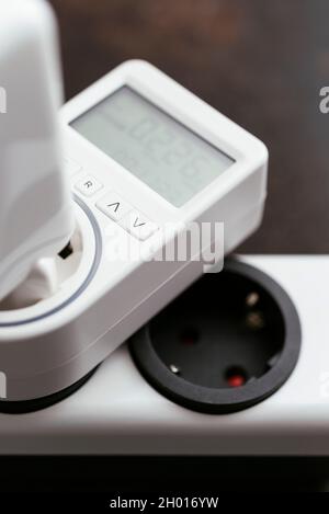 Electricity usage monitor measuring the standby power consumption of a laptop power supply. Stock Photo