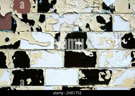 Brick wall with peeling black paint background. Surface texture with tile brick. Brick wall texture in old white paint closeup. Old grunge wall backgr Stock Photo