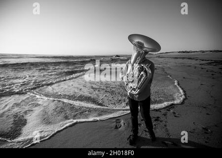 A musician with a tuba on the seashore. Black and white photo. Stock Photo