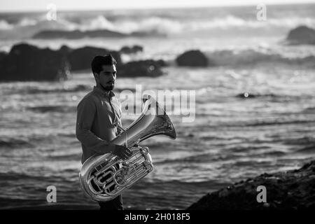 A musician man with a tuba on the Atlantic seashore. Black and white photo. Stock Photo
