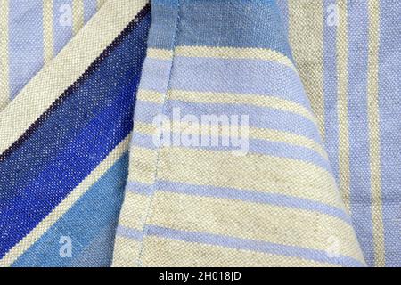 Gray linen fabric with a thin lilac strip, background. Linen fabric texture. Kitchen towel close-up. Home textiles made from natural fabric. Stock Photo