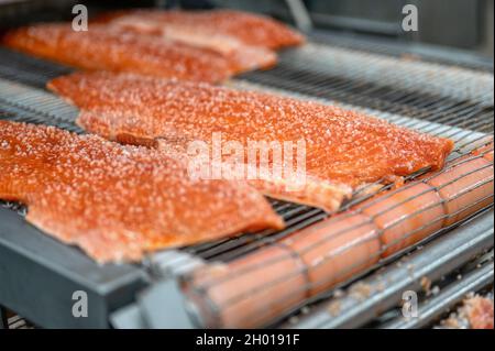 Many pieces of red fish fillet, salmon lie on a metal conveyor Stock Photo