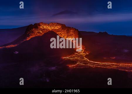 Lateral flow of lava from the crater from the volcanic eruption in Iceland. Crater from Fagradalsfjall volcano at night to the blue sky. Volcano Stock Photo