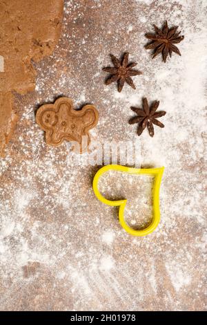 Gingerbread man cookie, three star anise fruits, cookie cutter in the shape of a heart and a piece of rolled out gingerbread sweet dough... Stock Photo