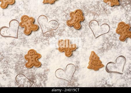 Festive holidays joyful pattern made of unbaked gingerbread man cookies, Christmas tree cookies and heart-shaped marks on the kitchen worktop. Stock Photo