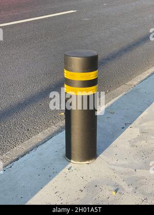Vertical shot of black street bollard with yellow reflective stripes on sunset Stock Photo