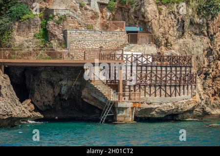 Cliffs with caves and stairs built in concrete, stone and metal next to the Mediterranean coast Stock Photo