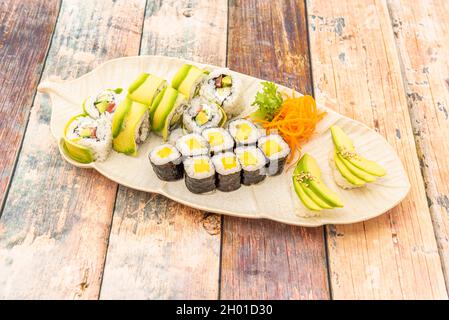 Maki and uramaki sushi tray with ripe mango and avocado with white rice and Japanese vinegar rolled in nori seaweed and sesame seeds Stock Photo