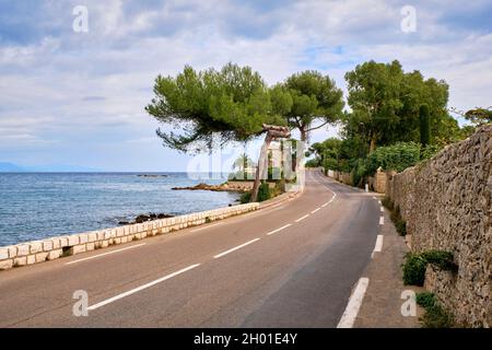 A narrow  curved road winds it's way along the shore of the Mediterranean Sea on the Cote D'Azur, Antibes France. Stock Photo