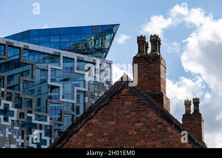 An old fashioned brick cottage in front of the modern Cube building in the centre of Birmingham, UK. Stock Photo