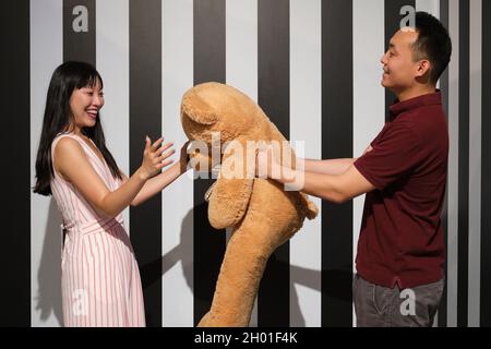 Young asian woman receive a teddy bear from her boyfriend on a striped room. Stock Photo