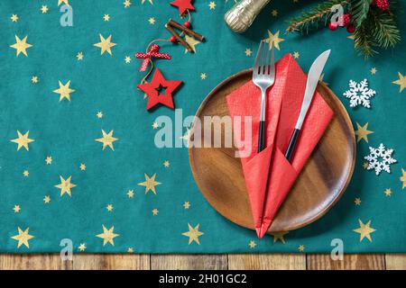 Table setting for Christmas dinner, holiday composition. Table fork and knife set with red paper napkin and fir branch on a rustic celebrate table. To Stock Photo
