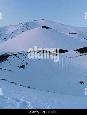 Snow covered landscape on Etna mountain and active volcano at sunset, in Sicily, Italy Stock Photo