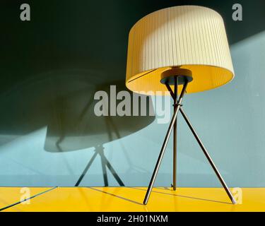 Closeup of a table lamp on a yellow designer sideboard in front of blue wall. Stock Photo