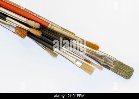 stack or group of used artists paintbrushes or equipment on a plain white background. artists paintbrushes  used and stacked in a pile. artusts tools. Stock Photo
